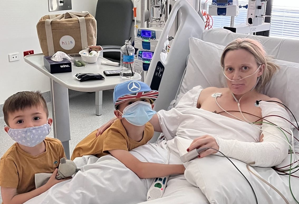 Woman in hospital bed with her two young boys