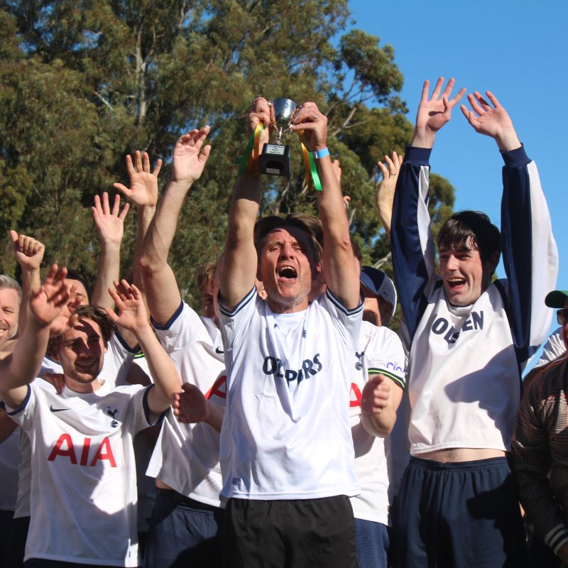 Group of men celebrating their win. Man in the middle holding a trophy