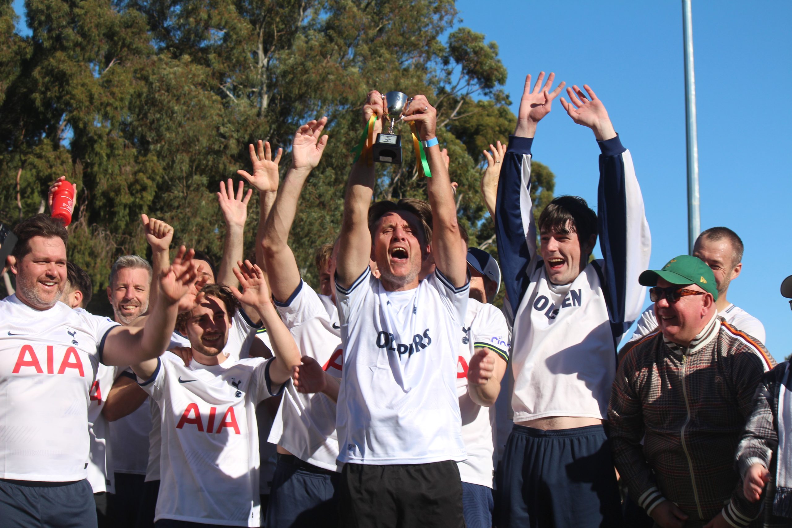 Group of men celebrating their win. Man in the middle holding a trophy